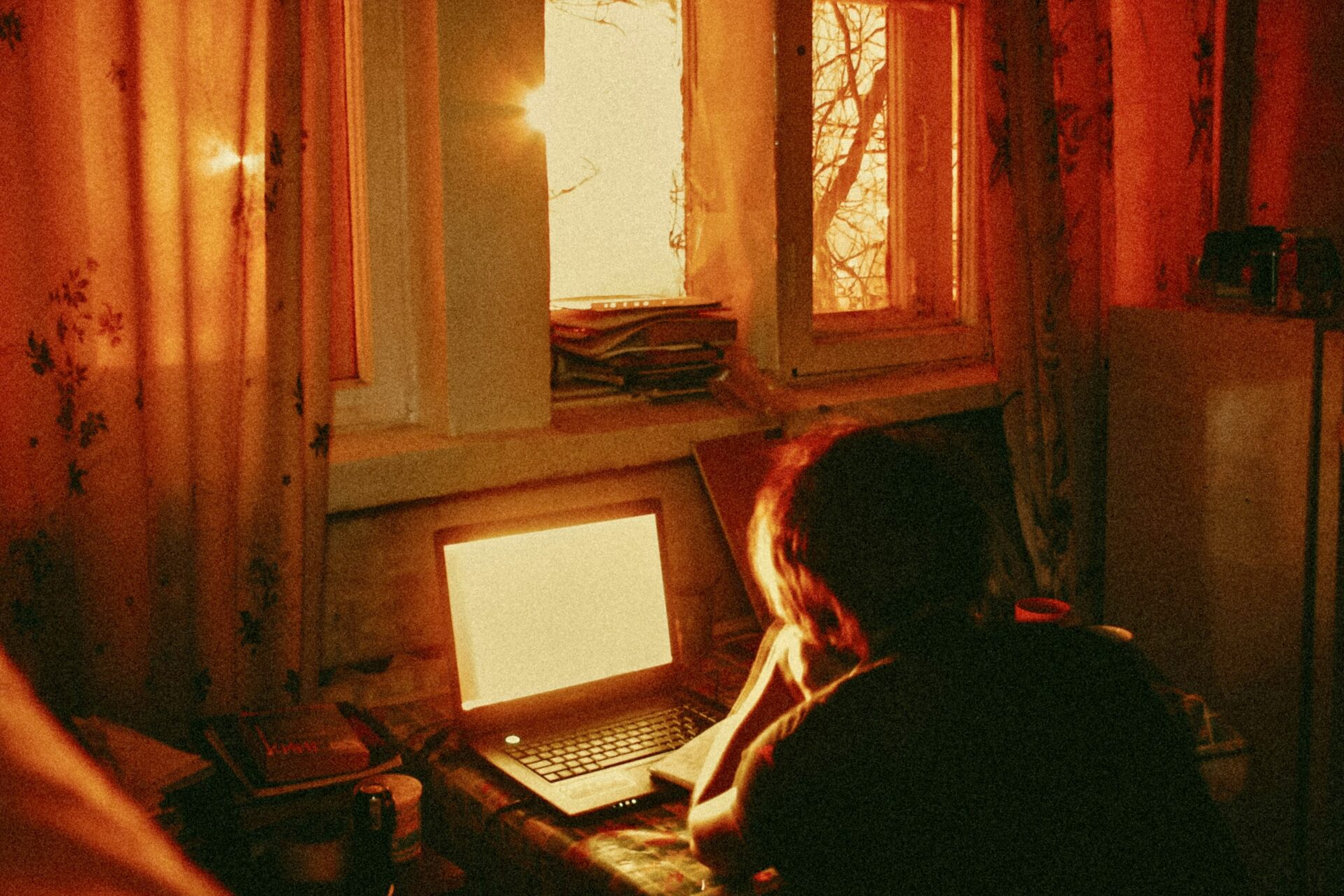 Person in red lit room on computer