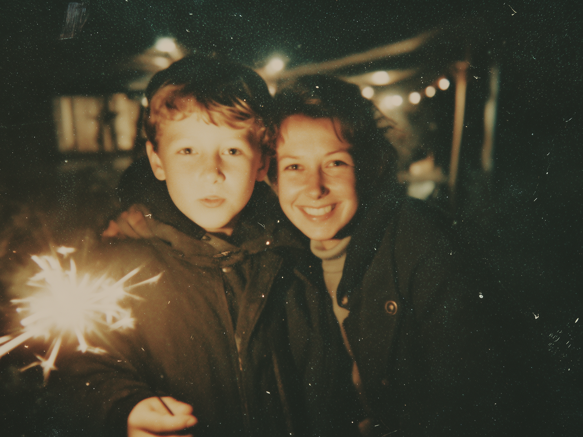 Nostalgic photo young boy and parent at night holding sparklers outdoors